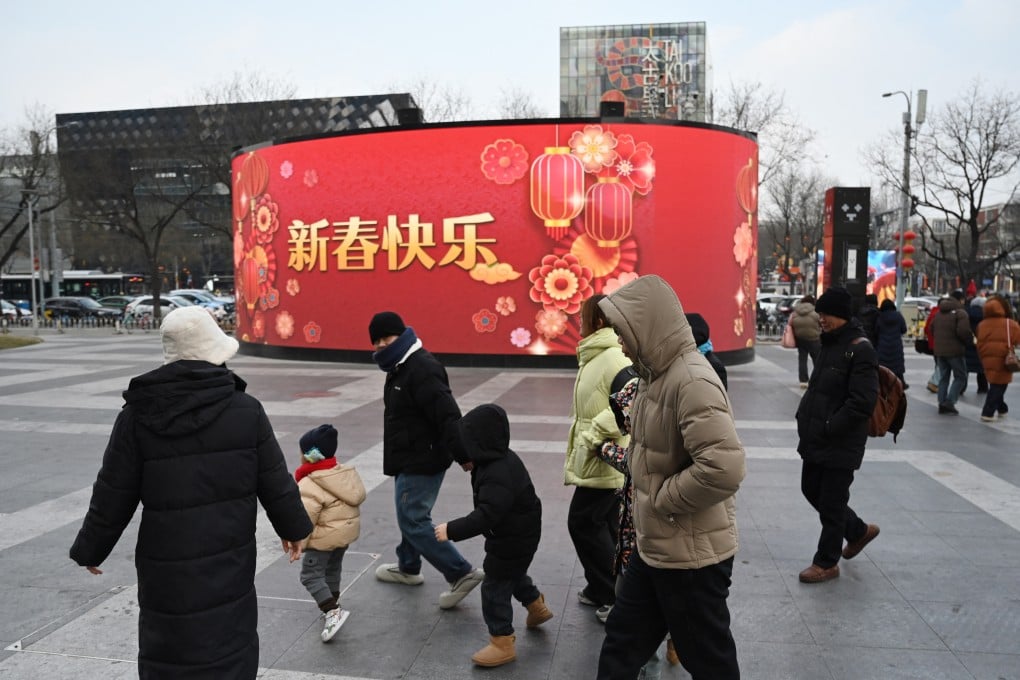 People walk past a festive display on a screen outside of a Beijing shopping mall during the Lunar New Year holiday on February 1. Photo: AFP