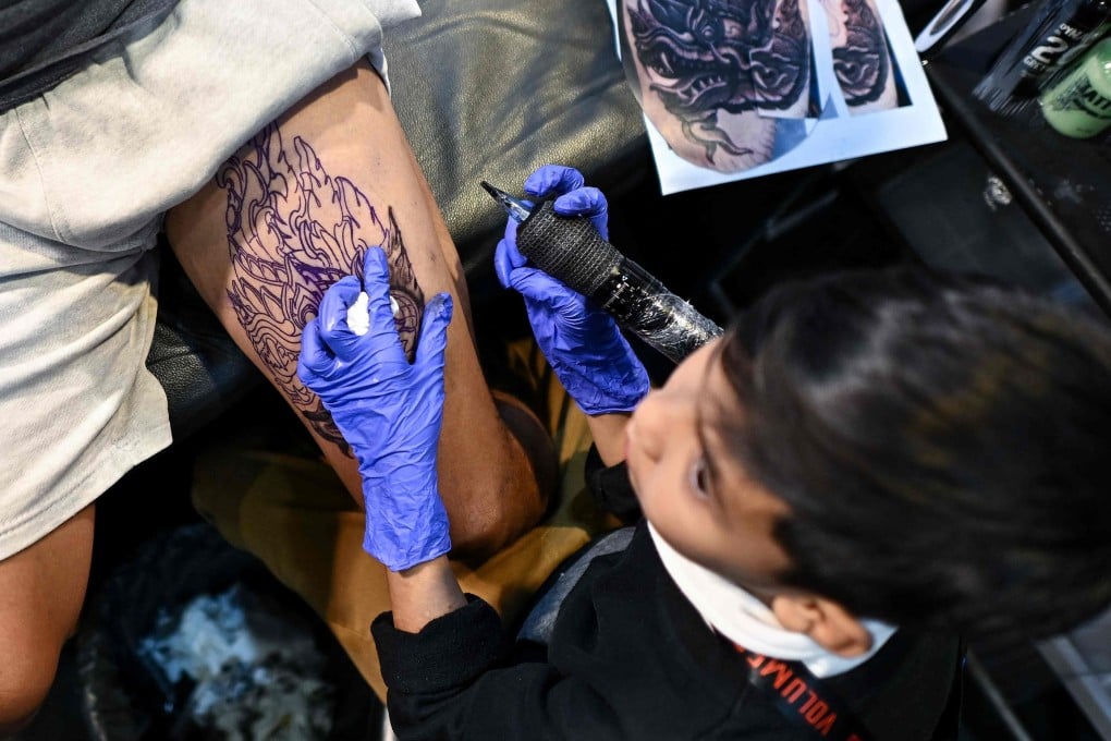 Nine-year-old Napat Mitmakorn, a Thai child tattoo artist, works on his uncle’s tattoo at the 2025 Thailand Tattoo Expo in Bangkok. Photo: AFP