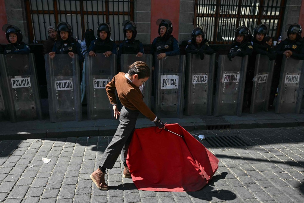 A young bullfighter performs a pass in front of a line of riot police in Mexico City. Photo: AFP