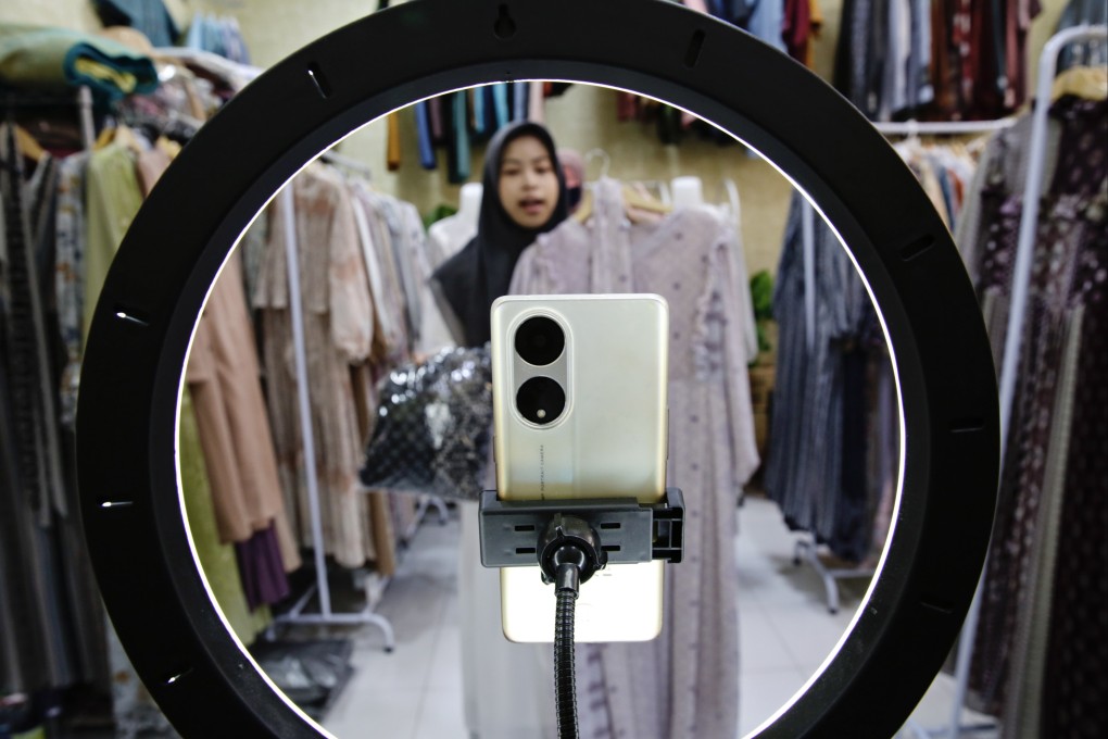 A woman holds a dress as she live-streams on an e-commerce platform at a shop in Depok, Indonesia, on September 28, 2023. The Indonesian government announced a regulation that bans social media sites such as TikTok and Instagram from selling goods and services directly. Photo: EPA-EFE