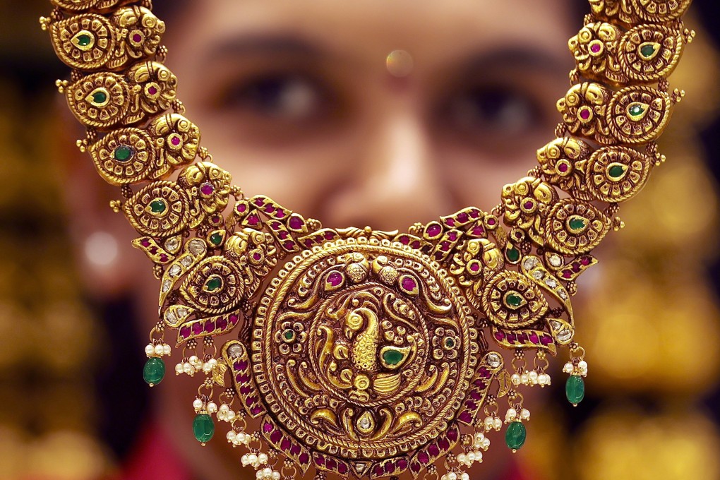 A vendor displays a gold ornament at a jewellery shop in Bangalore, India, on March 19. Gold prices have been soaring worldwide, fuelled by growing risk aversion. Photo: EPA-EFE