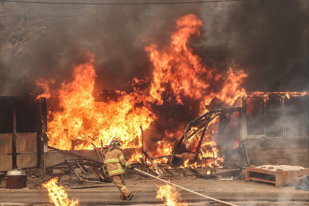 A firefighter works to battles that flames at a house engulfed by wildfire in Uiseong, South Korea, on Tuesday. Photo: Yonhap/AP