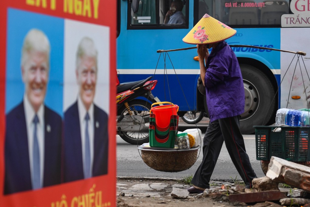 A street vendor in Hanoi walks past a poster featuring an image of US President Donald Trump in 2020. Photo: AFP