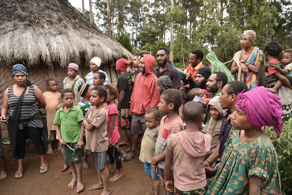 Neighbours gather near the home of a 55-year-old mother of two in the Tsak Valley in the Highlands of Papua New Guinea after she was accused of sorcery and tortured. Photo: AFP