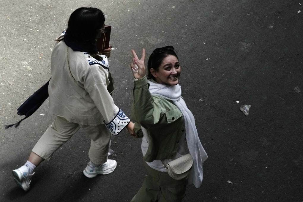 An Iranian woman without a mandatory hijab flashes a victory sign as she walks at the old main bazaar of Tehran, Iran, on June 13, 2024. Photo: AP