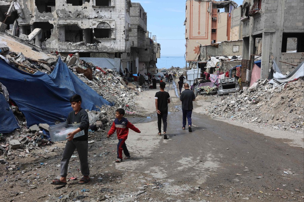 Palestinians walk past destroyed buildings in Gaza City on Friday. Photo: AFP