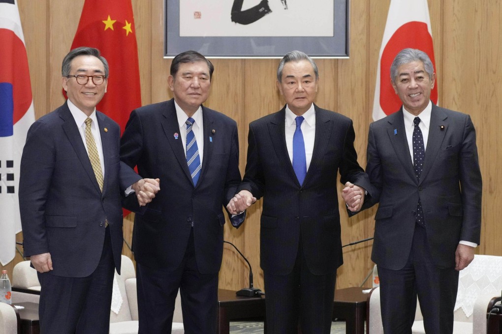 From the left, South Korean Foreign Minister Cho Tae-yul, Japanese Prime Minister Shigeru Ishiba, Chinese Foreign Minister Wang Yi and Japanese Foreign Minister Takeshi Iwaya join hands at the prime minister’s office in Tokyo on March 21. Photo: Kyodo