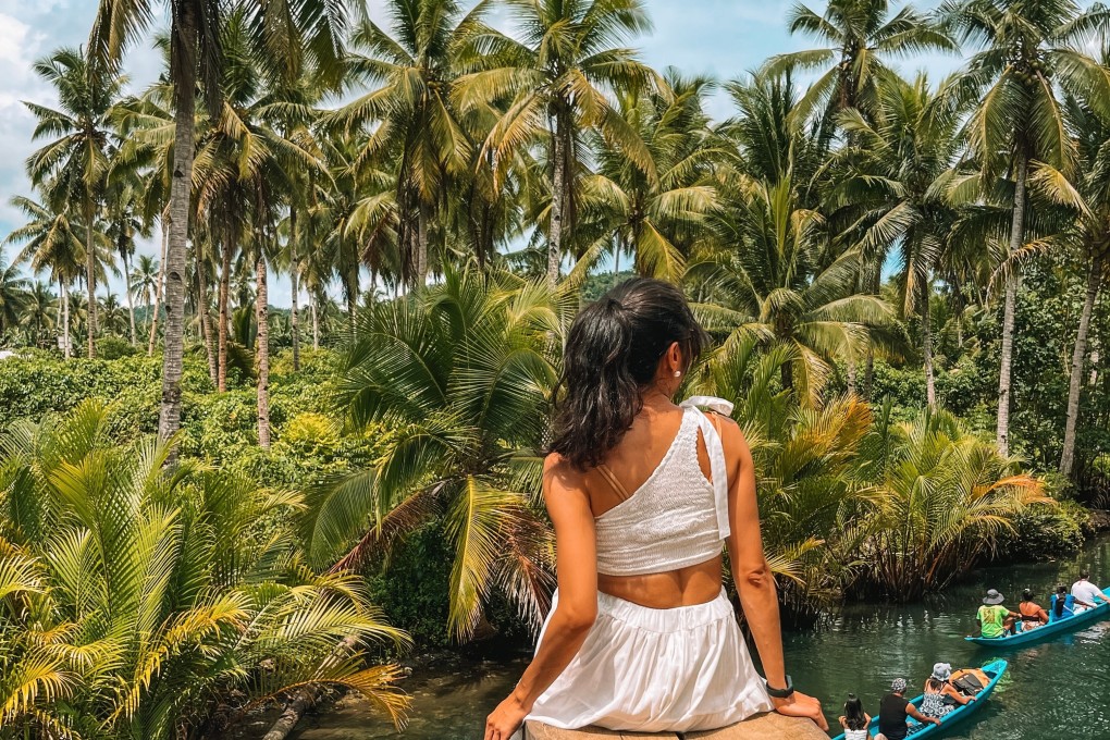 A traveller looks out over the lush palm trees and clear waters of the Maasin River on the island of Siargao, Philippines. Photo: Shutterstock