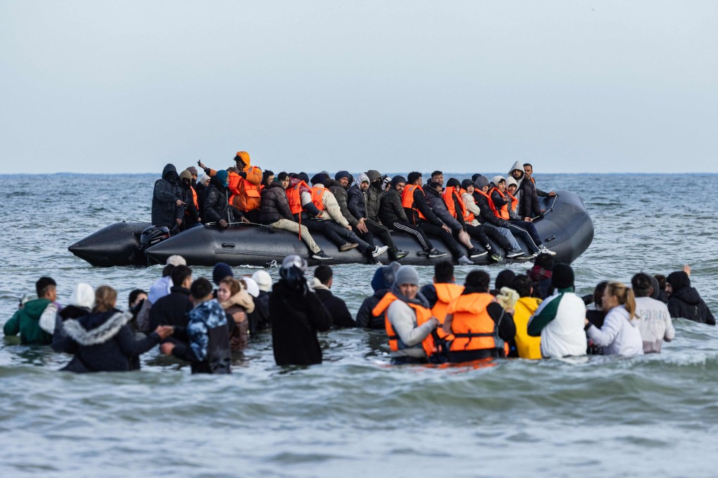 Migrants board a smuggler’s boat in an attempt to cross the English Channel, off the beach of Gravelines, north of France. Photo: AFP