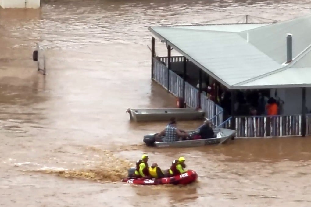 Rescue workers taking residents from a house on a flooded street in the town of Adavale in southwest Queensland. Photo: Queensland fire Department/AFP