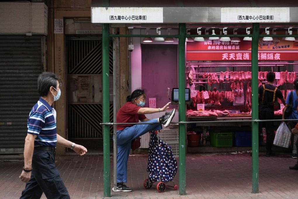 A woman finds a use for a bus stop railing while running an errand in Sham Shui Po, Hong Kong, on October 20. Photo: Eugene Lee