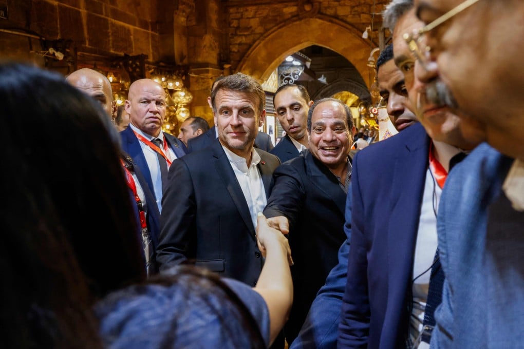 French President Emmanuel Macron (centre left) and Egyptian President Abdel Fattah al-Sisi, centre, greet people at the Khan al-Khalili market area in Cairo on Sunday. Photo: AFP