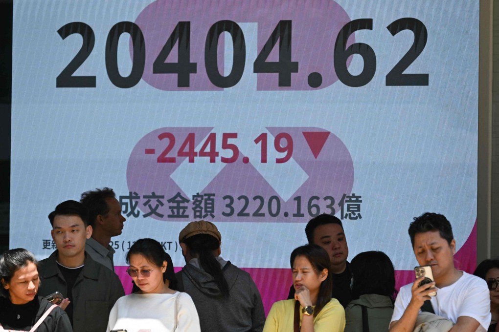 People stand in front of an electronic sign board in Hong Kong showing the Heng Seng Index on April 7. Asian equities collapsed on a black Monday on April 7 for markets after China hammered the United States with its own hefty tariffs, ramping up a trade war many fear could spark a recession. Photo: AFP