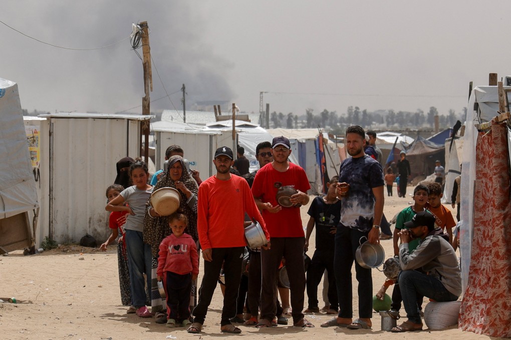 Smoke rises from an Israeli strike as Palestinians wait to receive food cooked by a charity kitchen in Khan Younis, southern Gaza, on Sunday. Photo: Reuters