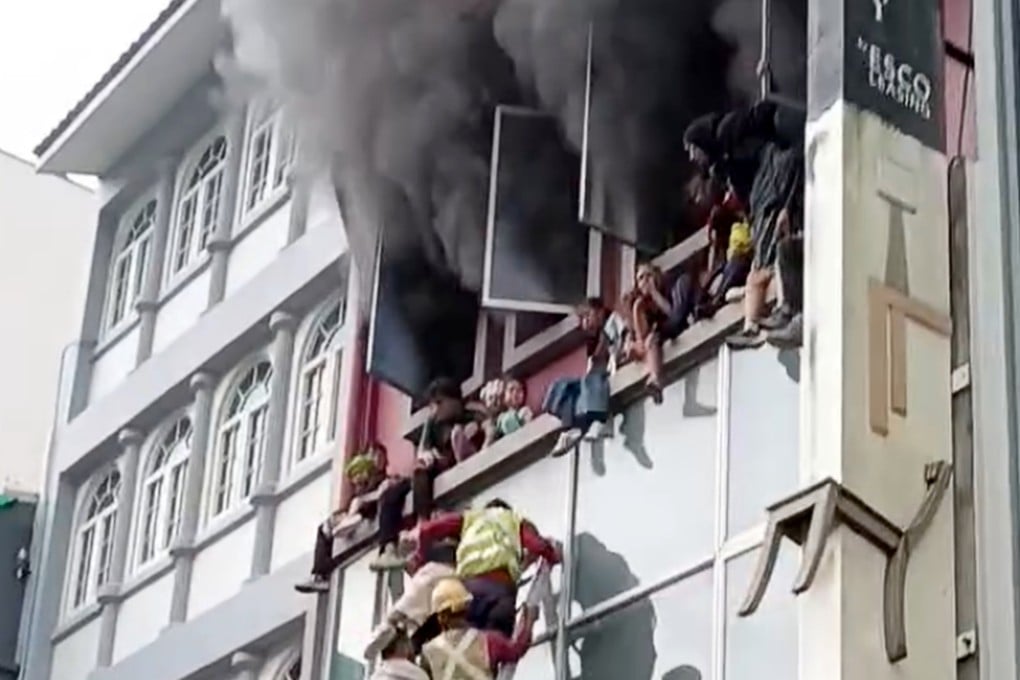 A still from a social media video shows migrant workers coming to the rescue of children trapped on the window ledge of a burning shophouse in River Valley, Singapore, on Tuesday. Photo: Handout
