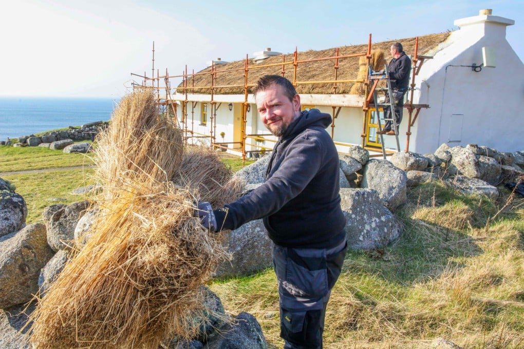 Trainee thatcher David McFarren (front), a student of the Donegal Thatching School, works on a thatched cottage in the village of Bunbeg, Ireland on March 9, 2025. Photo: AFP