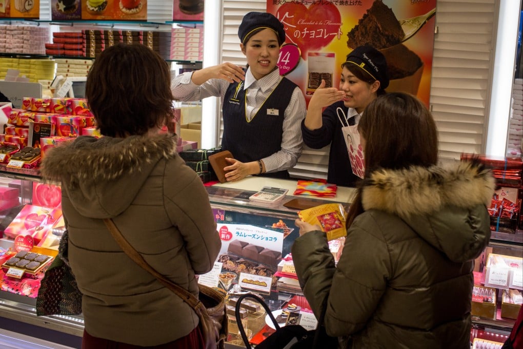 Sales staff discuss specialty chocolates with shoppers at a chocolate store in Tokyo, Japan. Photo: Getty Images