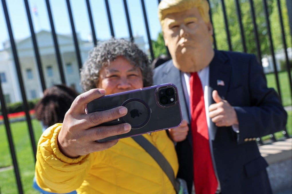 A tourist uses an iPhone to take a selfie with Donald Trump impersonator Ed Weiskopf in front of the White House in Washington, April 9, 2025. Photo: Reuters