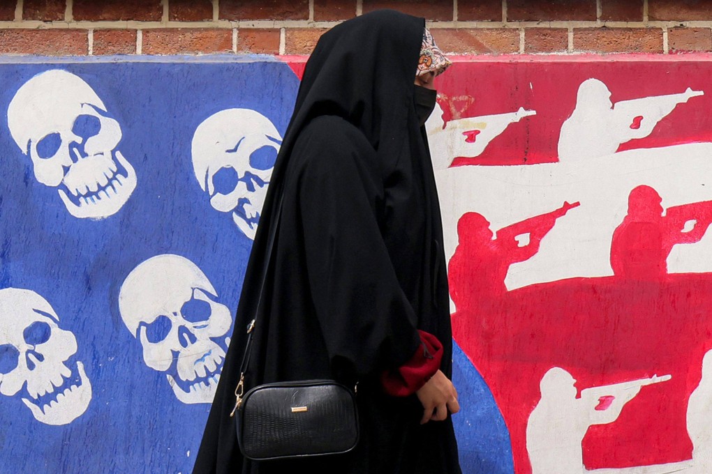 A woman walks past a mural depicting the US flag with the stars replaced by skulls and the white and red stripes with silhouettes of soldiers firing assault rifles, painted on the outer walls of the former US embassy in Tehran on Tuesday. Photo: AFP