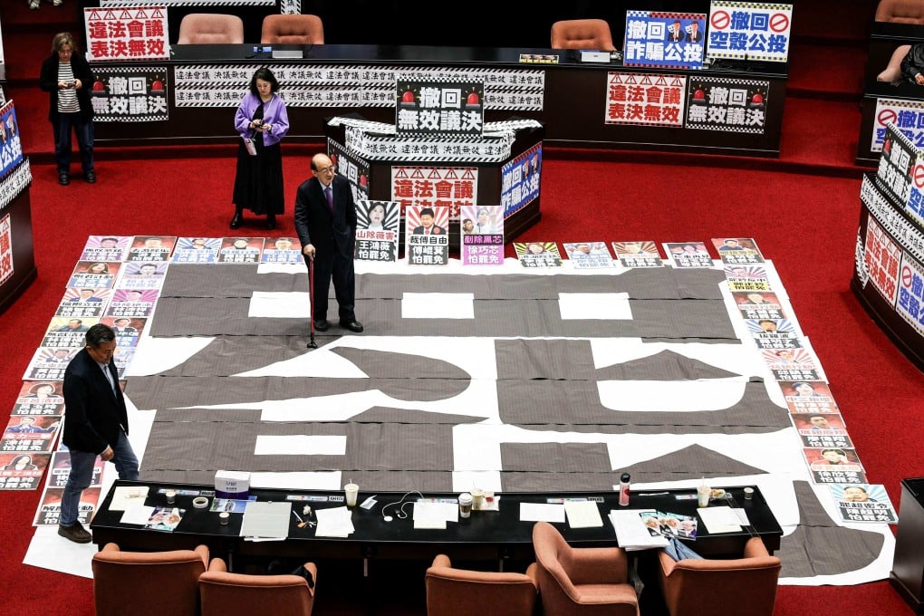 DPP lawmaker Ker Chien-ming (centre) stands on a poster with the word “recall” at the Legislative Yuan in Taipei on March 28. Photo: AFP