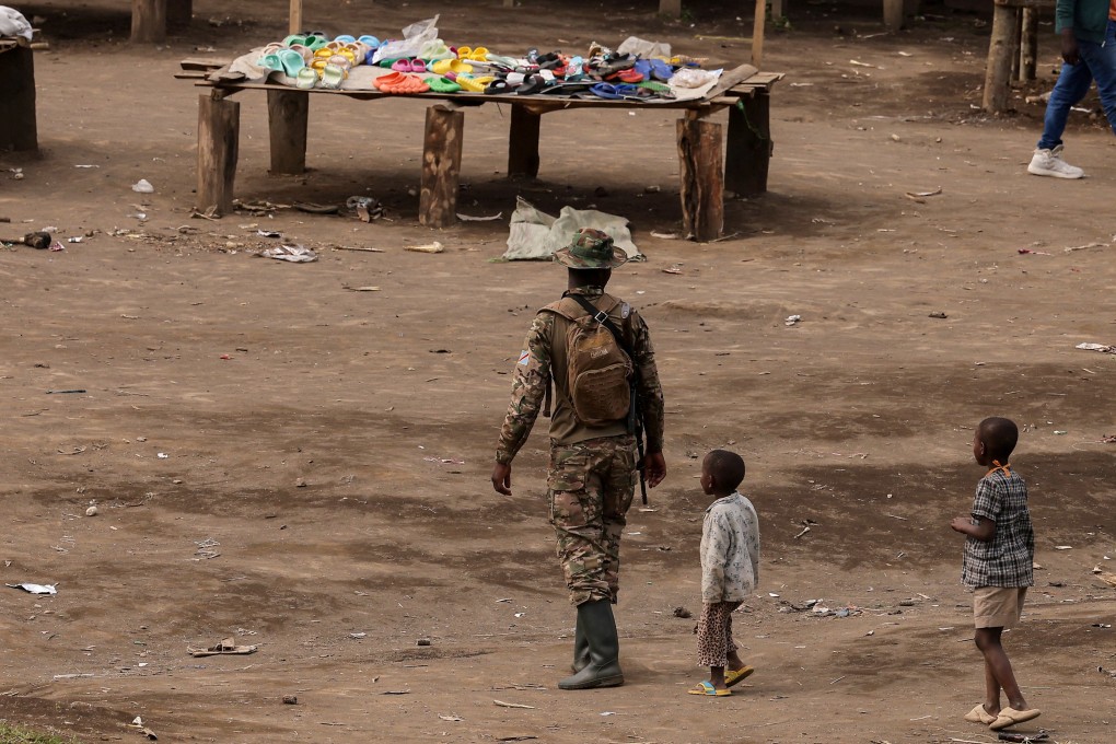 Children walk near an M23 rebel in Mushaki, in the Democratic Republic of Congo, in March. Photo: Reuters