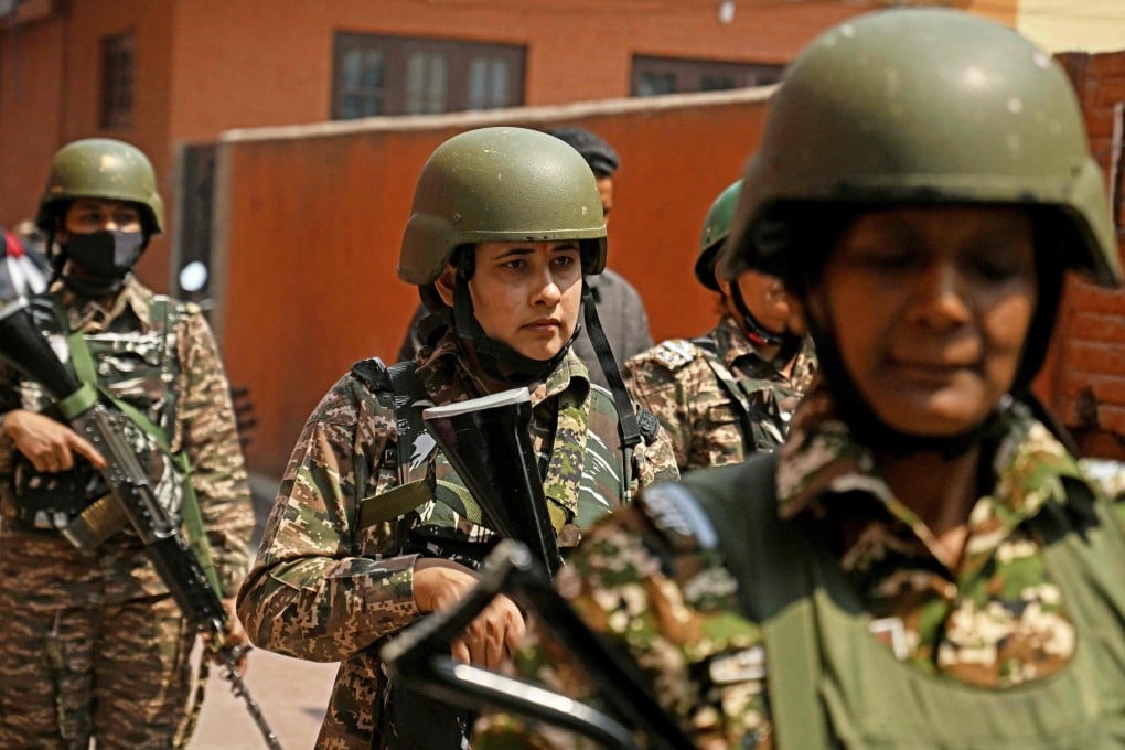 Paramilitary personnel stand guard as Kashmiri Anganwadi workers stage an anti-government protest demanding better pay and job security, in Srinagar on Monday. Photo: AFP