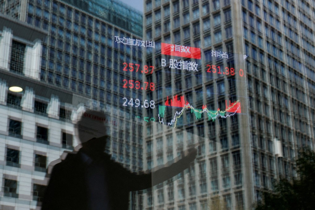 A person and buildings are reflected on the glass of a brokerage house where a stock information display board is hung inside, on April 9. Photo: Reuters