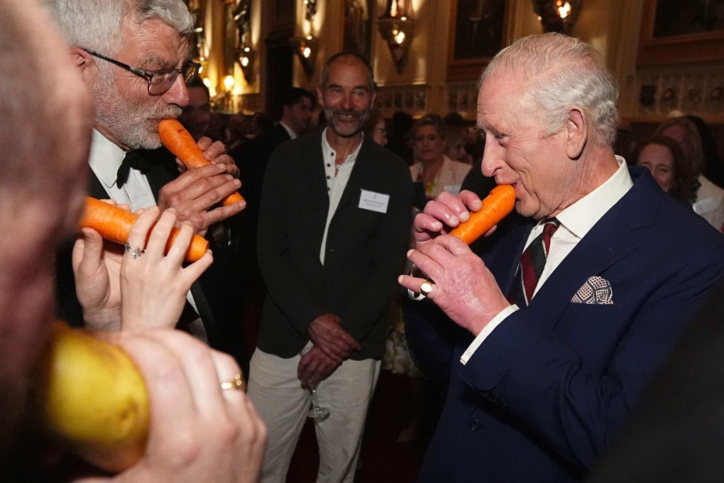 Britain’s King Charles III (R) plays a carrot with the London Vegetable Orchestra during a reception to recognise those involved in community music across the UK. Photo: AFP