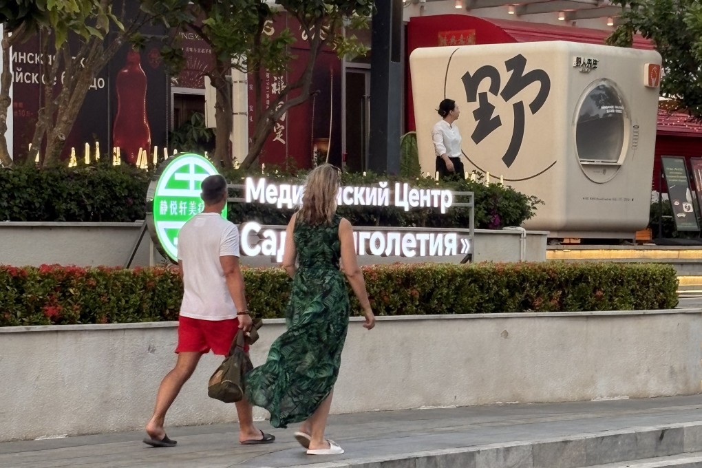 A couple walks past a Russian-language sign advertising a restaurant in Sanya, Hainan province. Photo: Sylvia Ma
