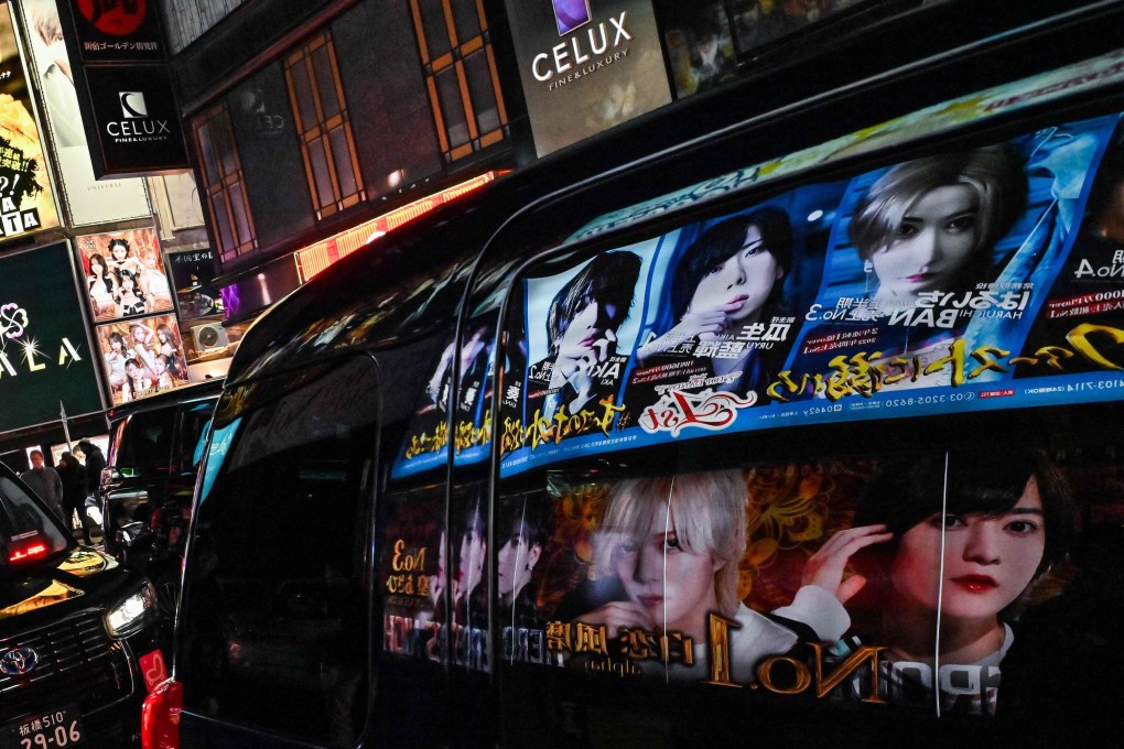 Advertisements for entertainment clubs are reflected in the window of a passing car in the Japanese red-light area of Kabukicho in Tokyo. Photo: AFP