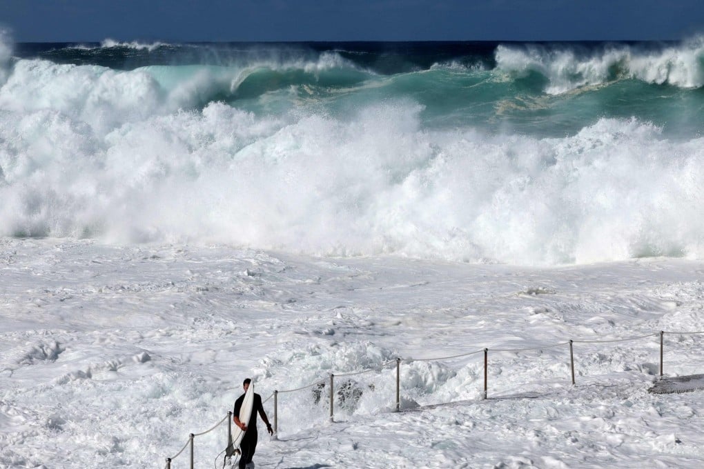 A surfer is dwarfed by large wave on Bronte Beach in Sydney on Friday as powerful swells hit Australias east coast. Photo: AFP