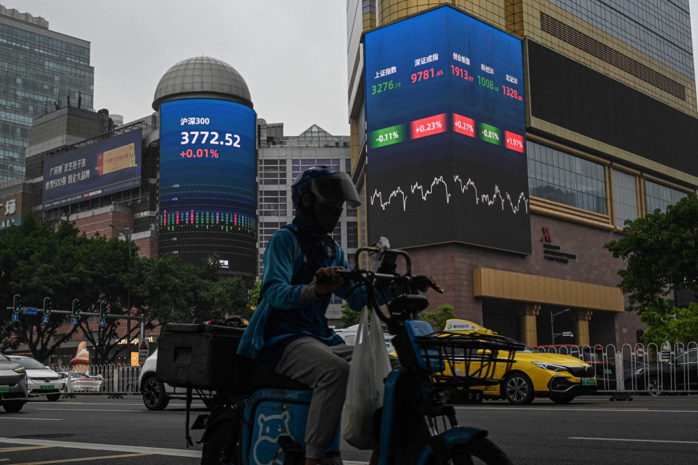 A delivery driver rides past screens showing stock market figures outside a shopping mall in Guangzhou. Photo: AFP