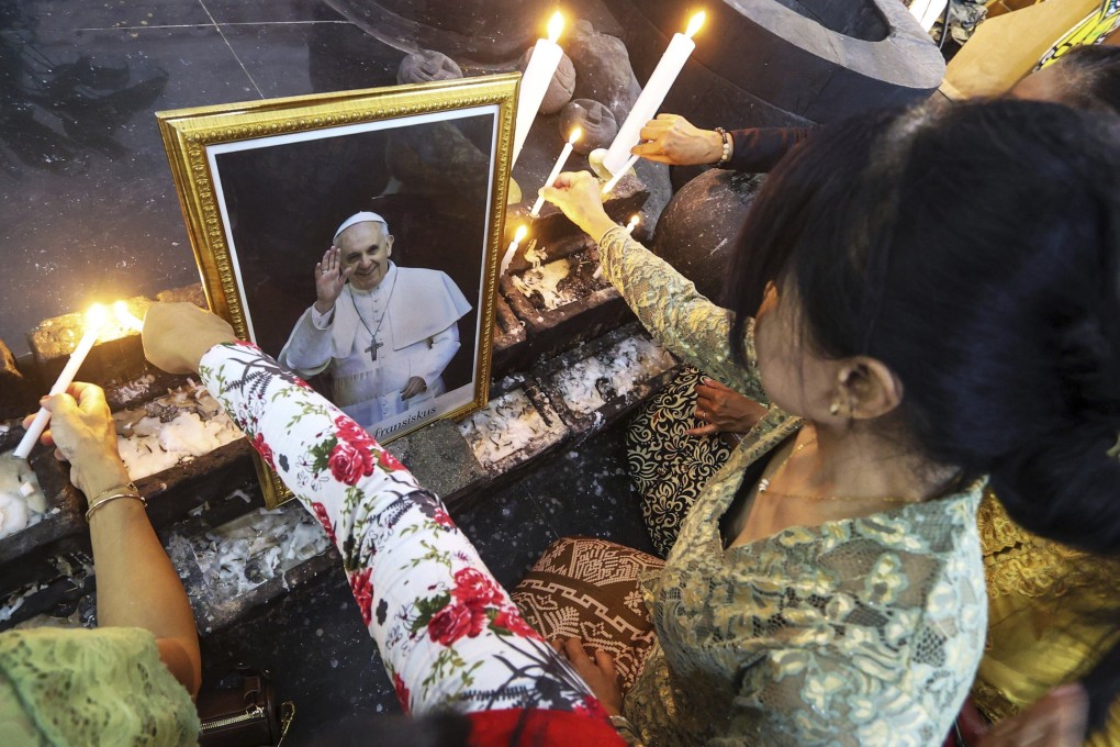Devotees light candles near a portrait of the late Pope Francis during a vigil at a church in Yogyakarta, Indonesia, on Monday. Photo: AP