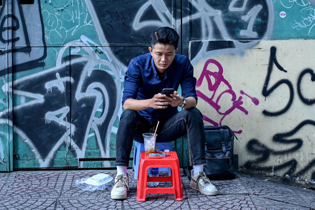 A man uses his smartphone as he sits on the pavement in Ho Chi Minh City. Vietnam’s crackdown on dissent now targets ordinary social media users, Human Rights Watch reports. Photo: AFP