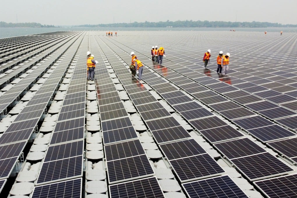 Workers walk between solar cell panels over the water surface of Sirindhorn Dam in Ubon Ratchathani, Thailand. Photo: Reuters