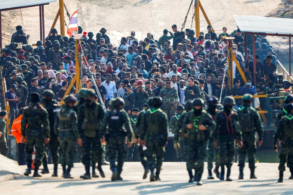 People of various nationalities who were tricked or trafficked into scam centres in Myanmar stand on a vessel as it passes to Thailand’s side of the border in February. Photo: Reuters