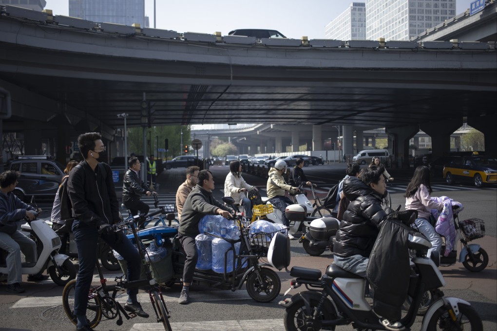 People riding bicycles and electric mopeds wait at a crossroad in the central business district of Beijing on April 10. Photo: EPA-EFE