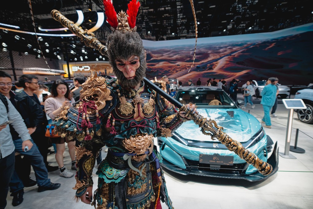 An actor in a fantasy costume poses in front of a BYD model L car during the Shanghai Auto Show. Photo: EPA-EFE