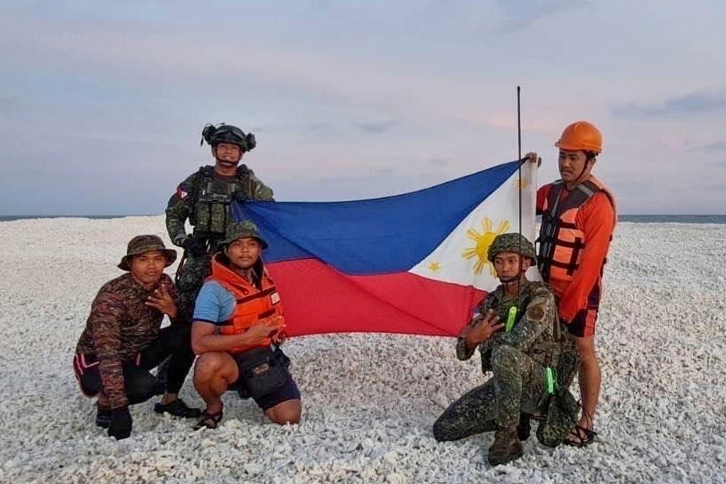 In this photo provided by the National Task Force West Philippine Sea (NTF-WPS), Philippine inter-agency members which included Philippine Navy, Philippine Coast Guard and Philippine National Police - Maritime Group, hold the Philippine flag as they visit Sandy Cay 2 in the South China Sea on April 27. Photo: AP