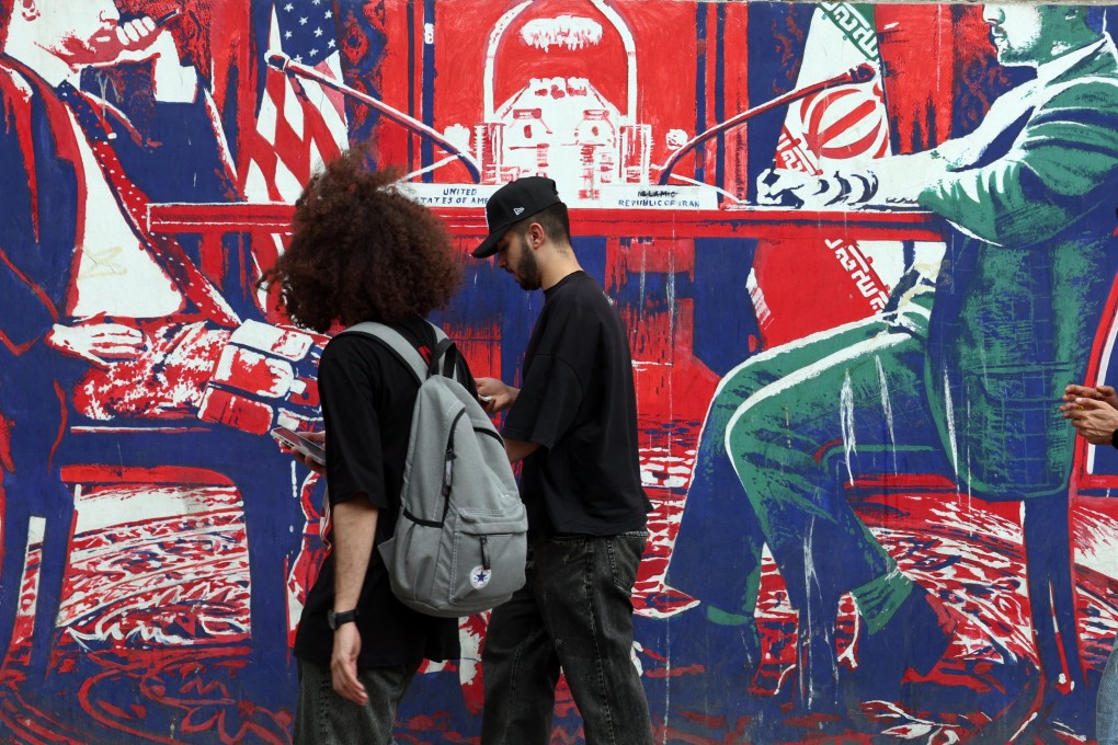 People walk next to a mural depicting Iran and the US negotiation table in a street in Tehran on April 26. Photo: EPA-EFE