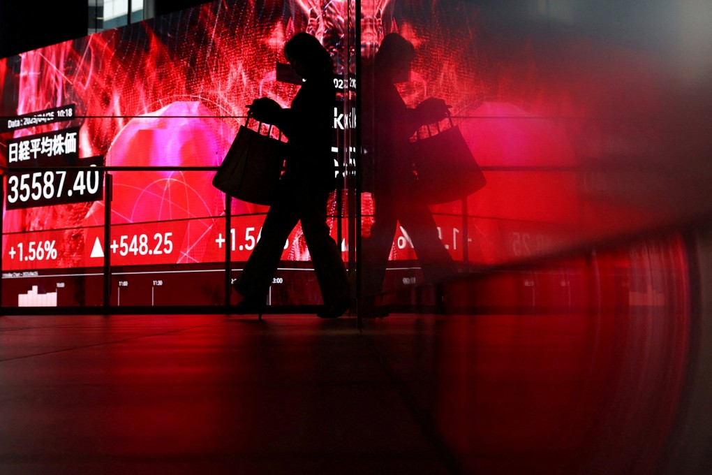 A woman walks in front of a screen displaying Japan’s Nikkei share average inside a building in Tokyo, Japan, on Friday. US tariffs have hit the country’s economy hard. Photo: Reuters