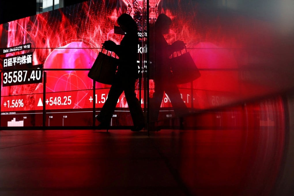 A woman walks in front of a screen displaying Japan’s Nikkei share average inside a building in Tokyo, Japan, on Friday. US tariffs have hit the country’s economy hard. Photo: Reuters