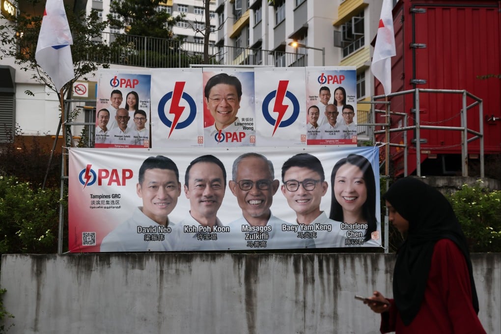 A resident walks past a banner showing Singapore’s Prime Minister and secretary general of the People’s Action Party Lawrence Wong (top) and candidates in a residential area in Singapore. Photo: EPA-EFE