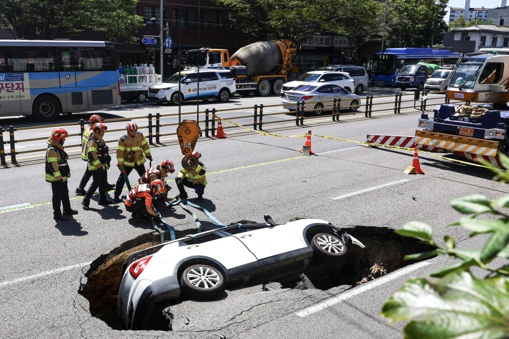 Firefighters in Seoul prepare to remove a car from a sinkhole in August last year. Photo: EPA-EFE