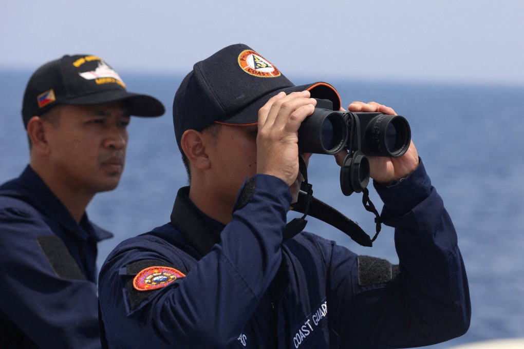 A Philippine coastguard official looks through binoculars while conducting a resupply mission for Filipino troops stationed at a grounded warship in the South China Sea, in October 2023. Photo: Reuters