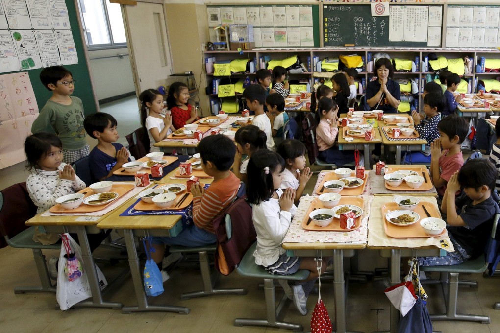 First-grade students and their teacher Teruko Takakusaki pose for a photo during lunch at Takinogawa Elementary School in Tokyo, Japan. Photo: Reuters