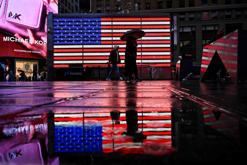 People walk past an electronic board displaying the American flag at Times Square in New York, on April 11. Photo: AFP
