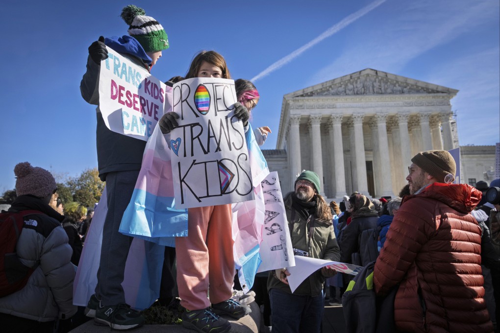 Children hold signs and transgender pride flags as supporters of transgender rights rally by the US Supreme Court in December. Photo: AP