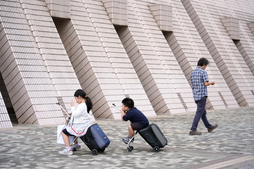 Two young tourists sit on their ride-on suitcases outside Hong Kong Cultural Centre in Tsim Sha Tsui. Photo: Eugene Lee