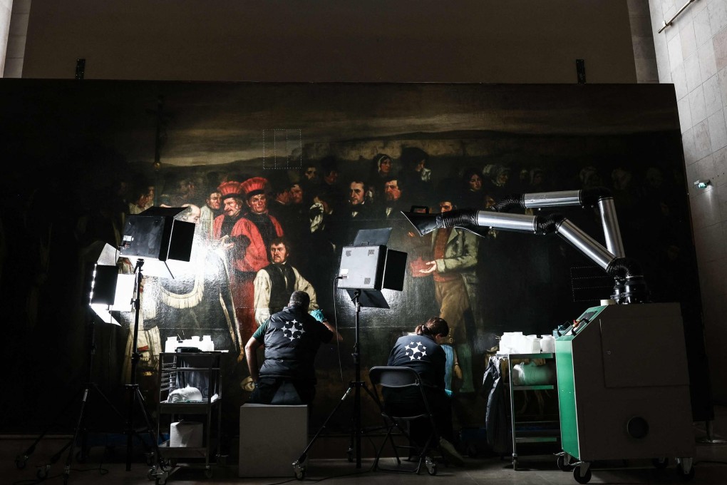 Art restorers work on Gustave Courbet’s painting titled A Burial at Ornans at the Orsay Museum in Paris. Visitors can observe the restoration of the masterpiece through large windows. Photo: AFP